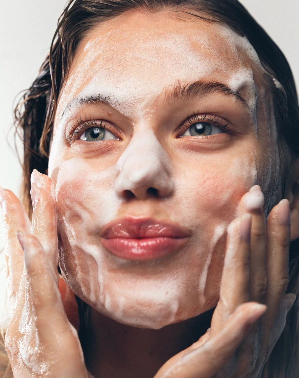 Chica con espuma de limpiador facial en la cara